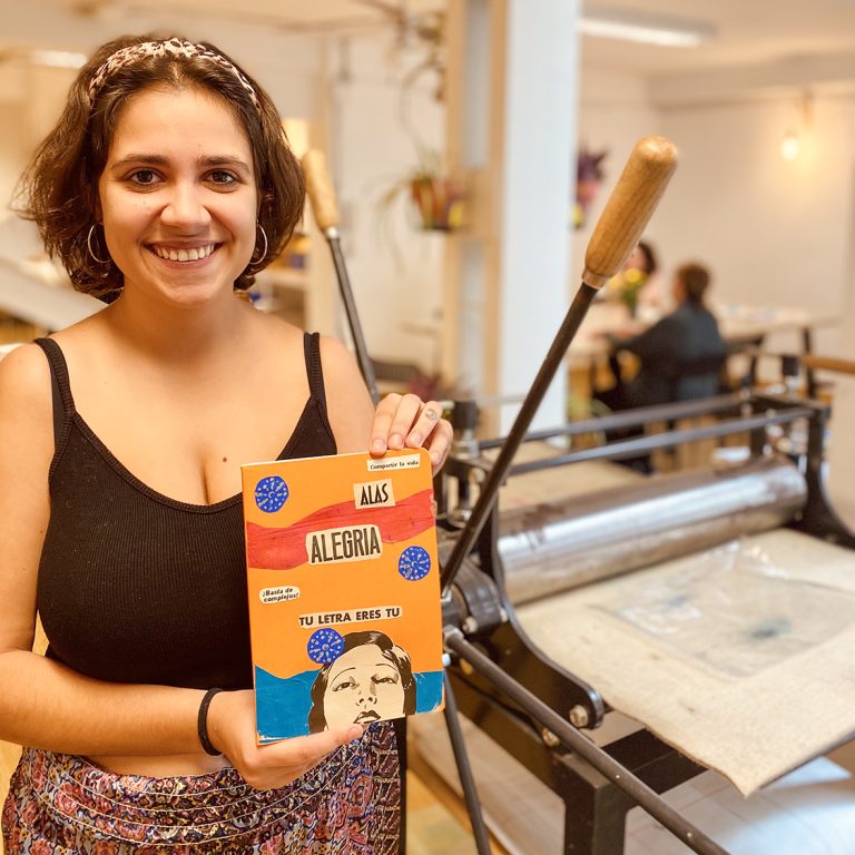 Chica mostrando cuaderno realizado con técnica de collage