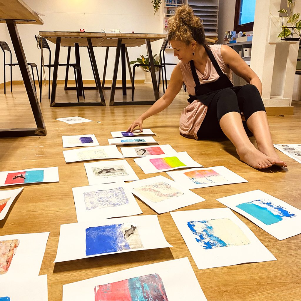 Chica sentada al suelo con un montón de obras de arte el suelo en papel